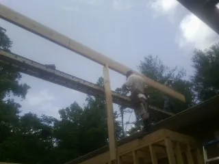 Carpenter setting a ridge beam over a new addition frame — Ice Dam Removal by Roofing Brothers in Marmora
