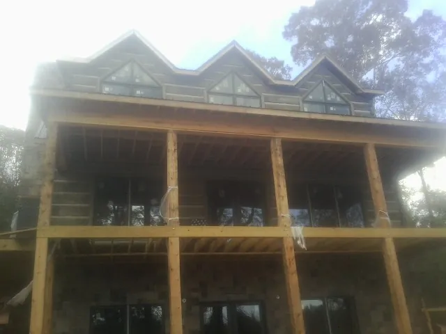 Dormers and porch framing on a large log home under construction — Roof Coating work by our crew in Marmora