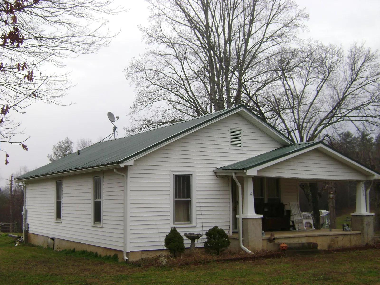 Green metal roof on a white bungalow with a side porch in Marmora