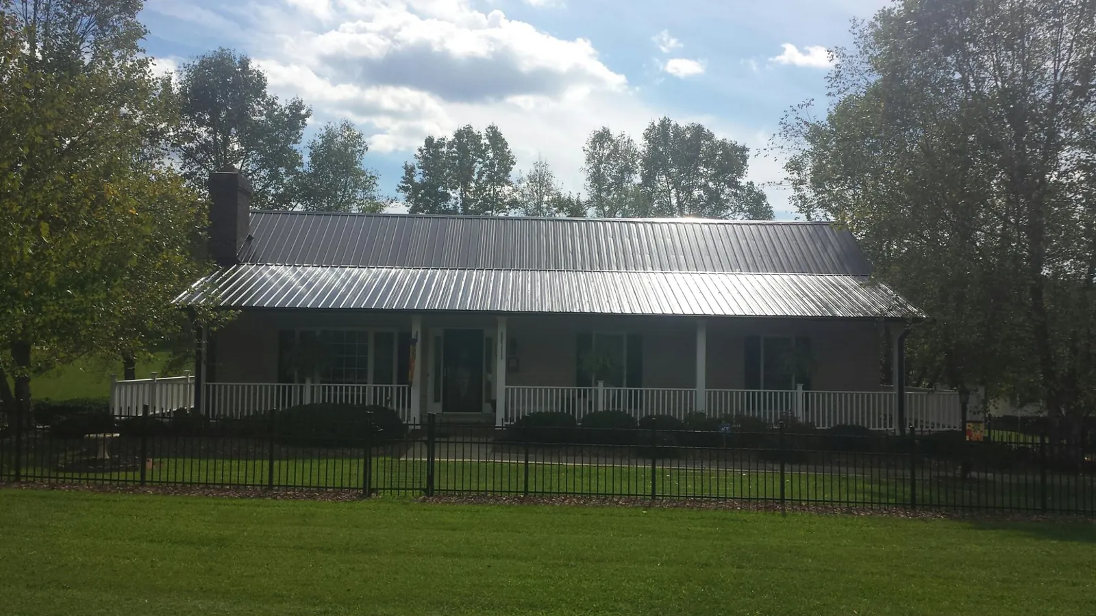 Gray metal roof on a brick ranch with a full width front porch — Gutter Guard Installation work by our crew in Marmora