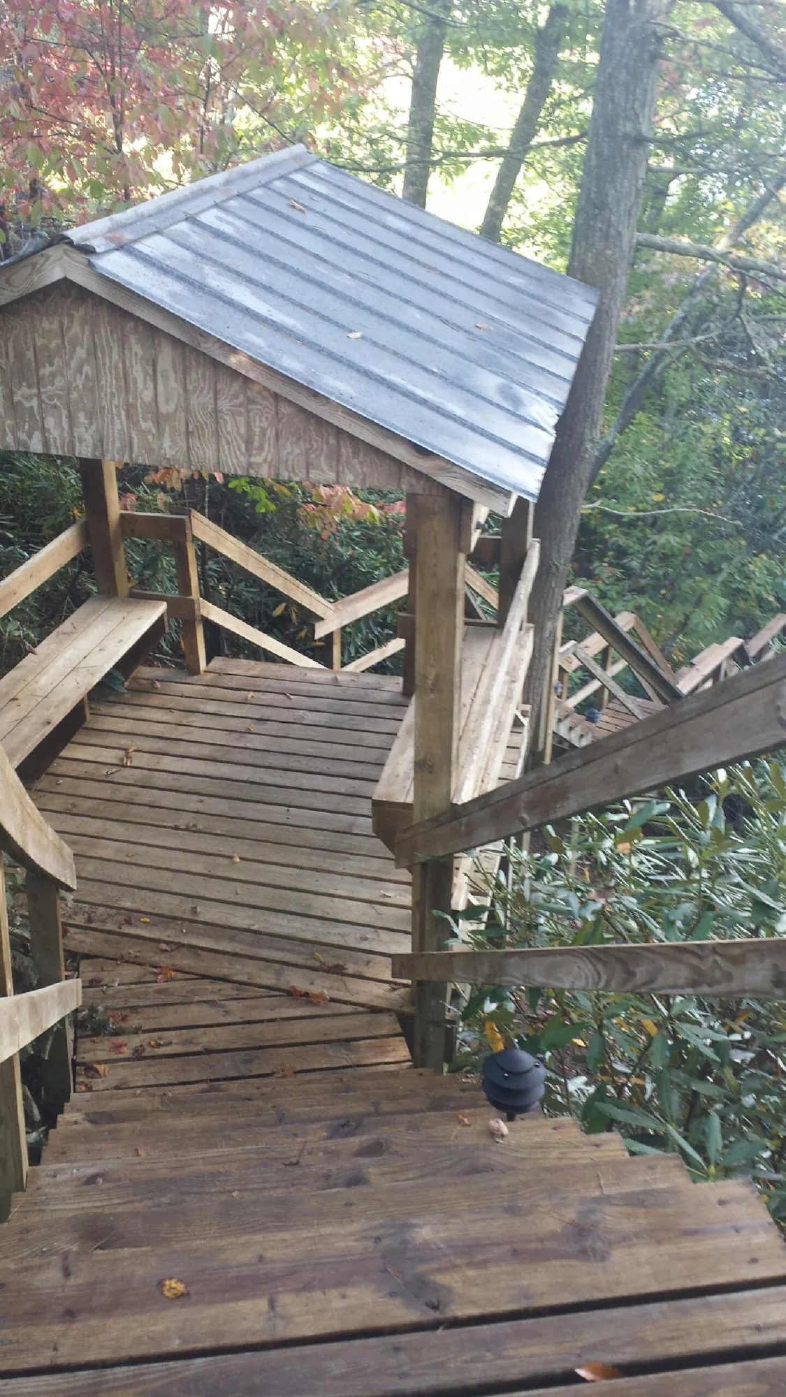 Metal roofed shelter over wooden steps on a wooded walkway — Skylight Repair & Installation work by our crew in Marmora