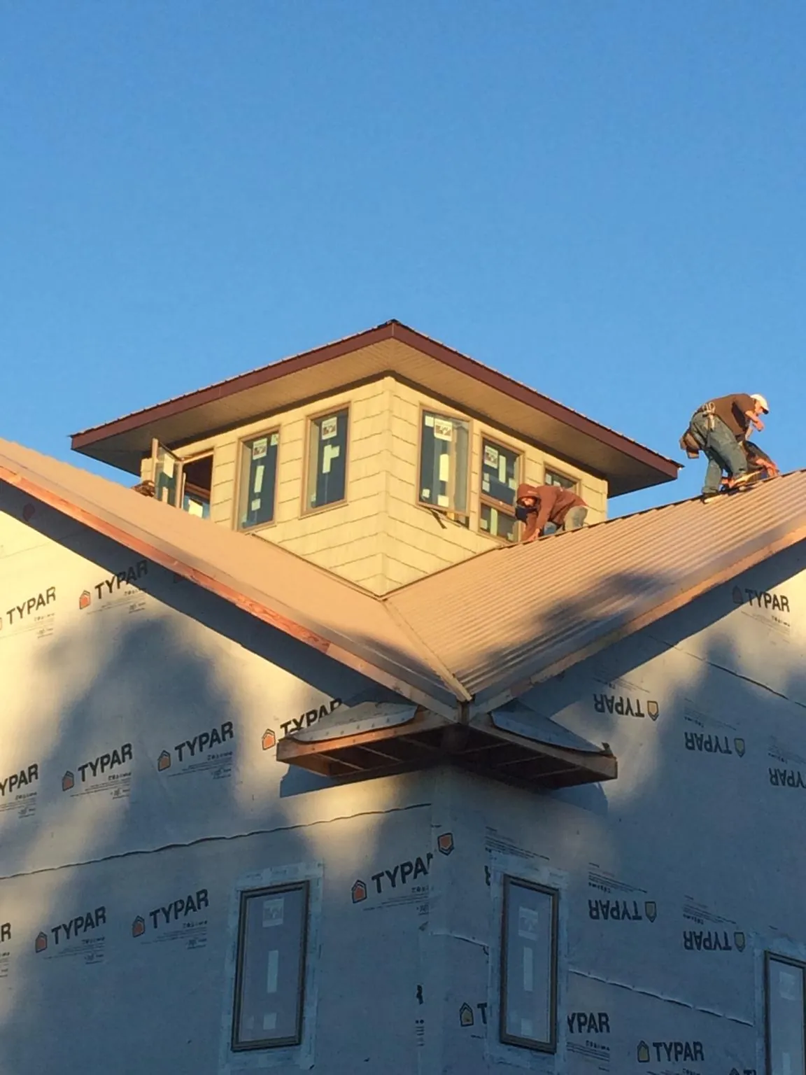 Roofers working around a rooftop cupola on a new metal roof at sunset — Roof Waterproofing in Marmora by Roofing Brothers
